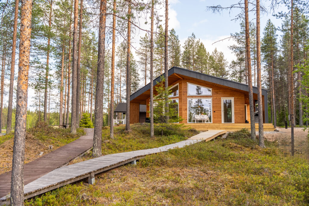 Moderni Nuuna mäntymetsän keskellä. Terassilta tulevat luiskat kohti rantaa.