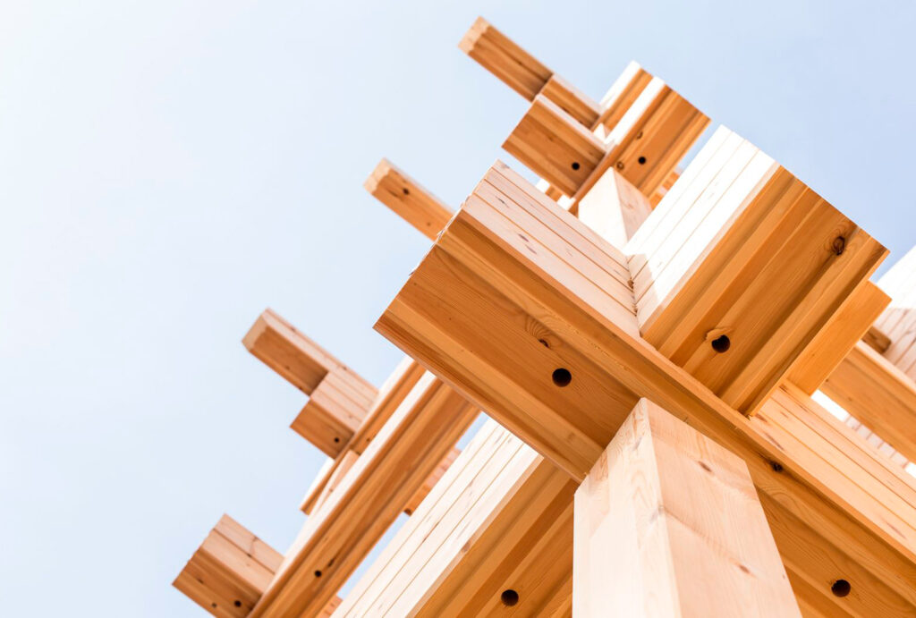 A log hotel frame with cross corner joints, photographed from below looking up towards the sky.