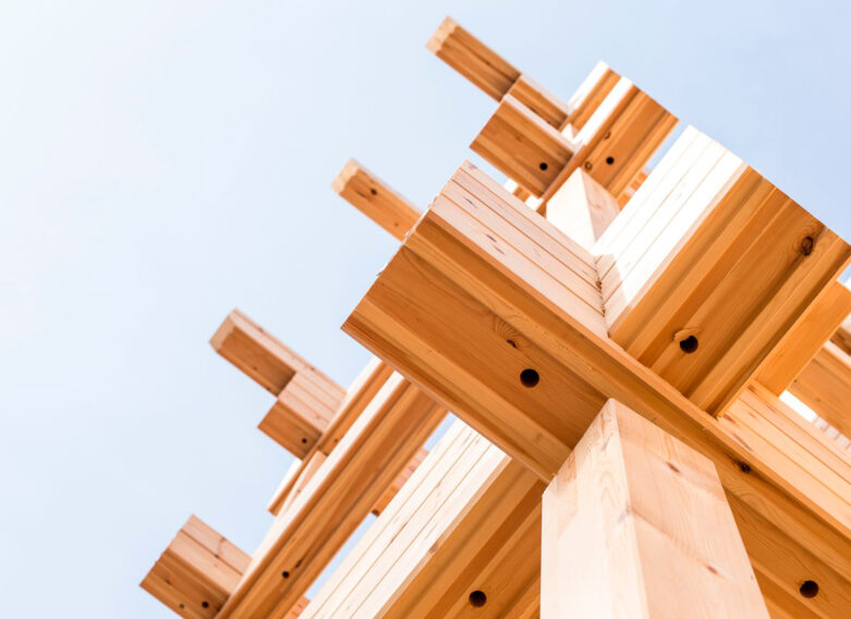 A log hotel frame with cross corner joints, photographed from below looking up towards the sky.