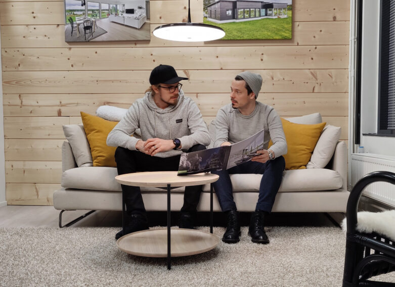 Två personer bläddrar i broschyren för Kuusamo Timmerhus.