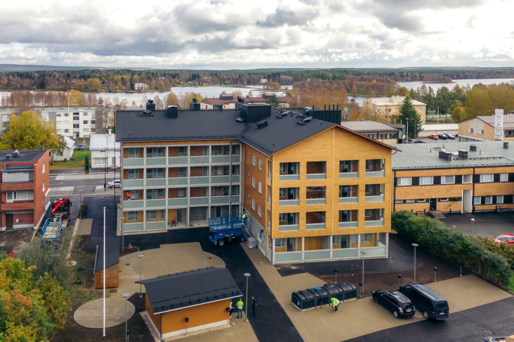 Hirsikerrostalo ilmasta kuvattuna. Kerrostalo on muodoltaan L-kirjaimen mallinen ja siinä on neljä asuinkerrosta.