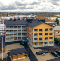 Timmerhus från luften. Huset är en L-modell och har fyra våningar.