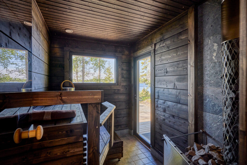 An interior view of the Mylly model from the Log Saunas range, featuring dark-toned walls and benches.