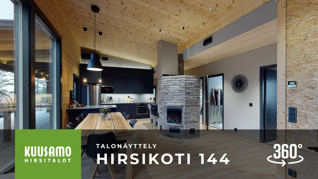 Hirsikodissa on tunnelmallinen kivistä tehty takka ja iso ruokailuryhmä. Takana näkyy mustat keittiökaapit.