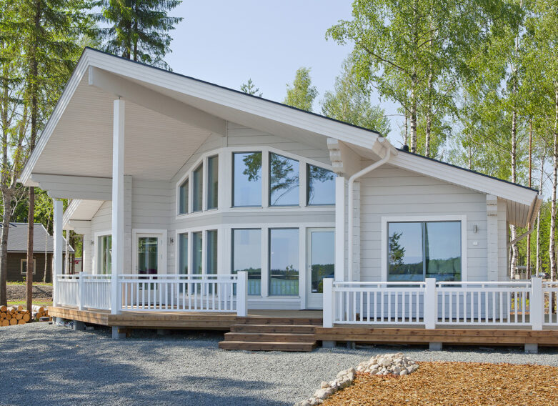 Täysin valkoinen, moderni hirsihuvila, jossa on isot ikkunat.