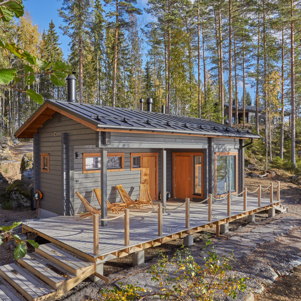 A grey-and-orange log sauna, built with a cross corner joint and a gable roof.