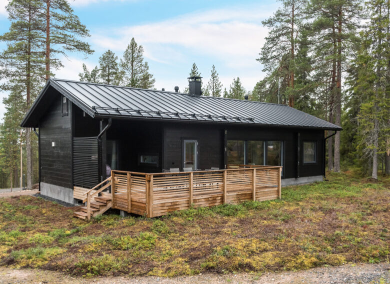 Tummaksi väritetty harjakattoinen hirsikoti Oulanka. Takapihalla on tilava terassi.