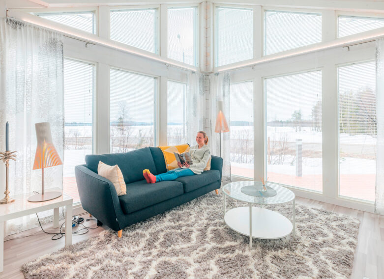 Susanna Saapunki läser en bok på soffan i timmerhuset.