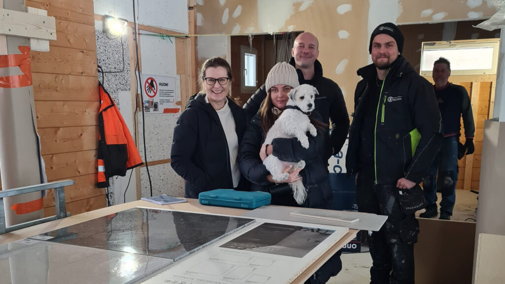 The house builders in a group photo with a dog. Villa Aurora, currently under construction, can be seen in the background.