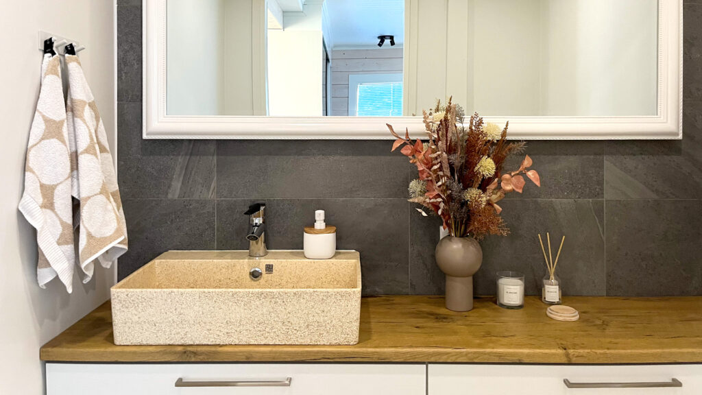 The washbasin in the WC. The basin itself is light-coloured and the countertop is wood-coloured.