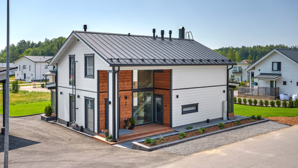 In the white log house, the entrance has been designed to appear as if it were embedded in the building. Next to the entrance, the logs have been treated to a light brown finish.