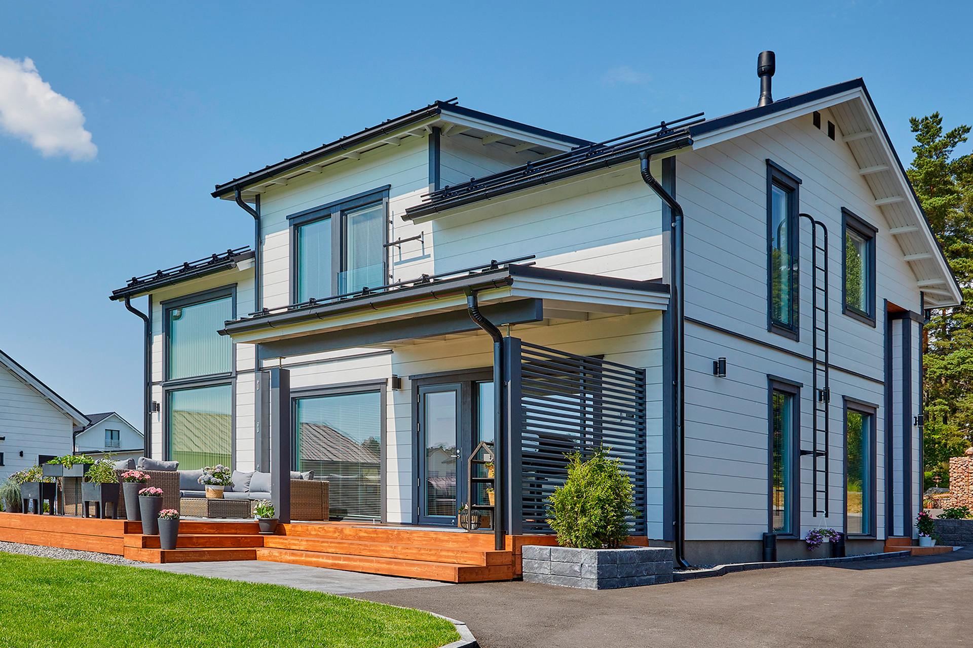 A white 1.5-storey log house with details in grey and black.