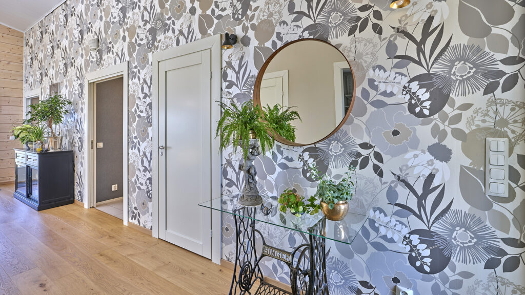 I mellanväggen i timmerhuset finns en tapet med blommönster i grått och beige. Den ger en behaglig livfullhet som komplement till de lugnande timmerytorna.