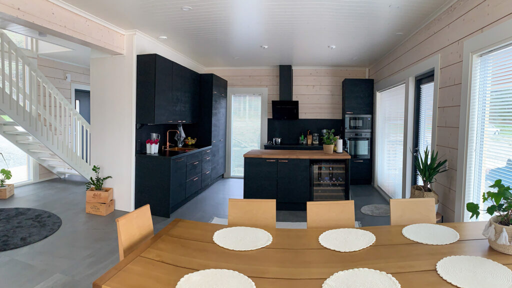 The black finish of the kitchen adds contrast to the otherwise light-coloured log home. The worktop is wood-coloured.