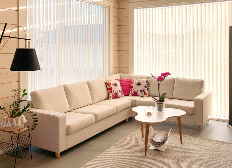 The bright living room of the log home. Light pink details have been added to complement the light tones, perfectly matching the atmosphere of the living room.