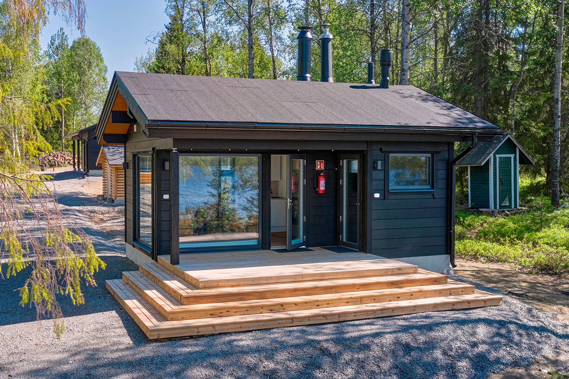 Moderni, harjakattoinen 25-neliöinen hirsisauna. Tuvan puolella on moderniin tyyliin sopivasti kahdelle suunnalle aukeavat isot ikkunat.