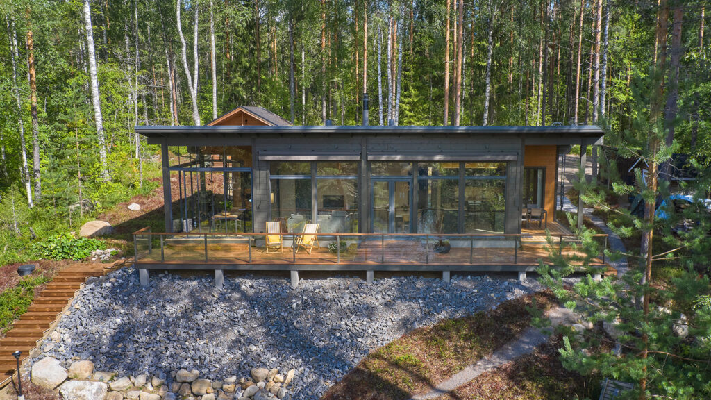 Pulpettikattoinen hirsihuvila yläviistosta kuvattuna. Rakennuksen etuseinä on lähes kokonaan ikkunoiden peitossa.