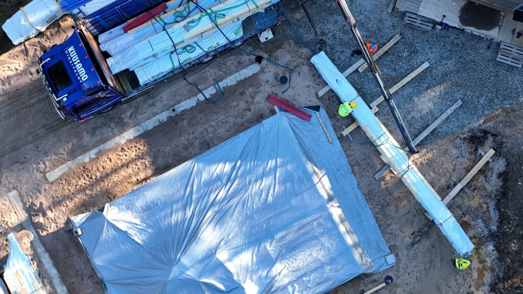 Asiakas on suojannut perustukset pressuilla sateen varalta. Hirsipaketit nostetaan mahdollisimman lähelle perustuksia.