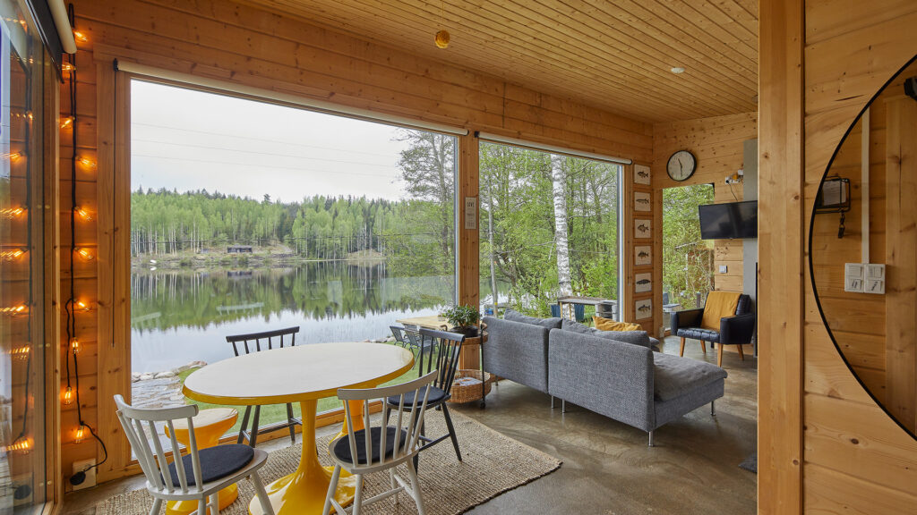 Modernin, pulpettikattoisen hirsimökin oleskelutila. Tilasta avaran ja valoisan tekee suuret ikkunat ja rakennuksen keulalle kohoava pulpettikatto.