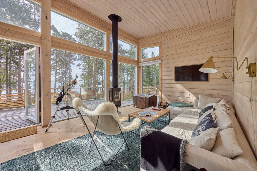 The living room of the log villa has floor-to-ceiling windows. There is a sofa on the opposite wall.