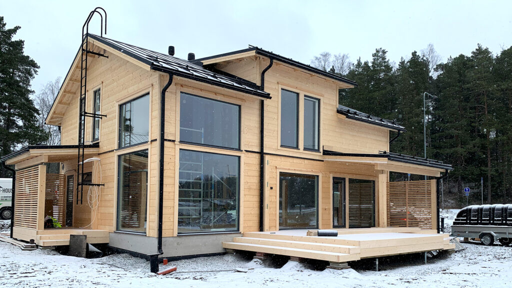 Ett modernt timmerhus med sadeltak under uppförande. Timmerstockarna har ännu inte bearbetats.
