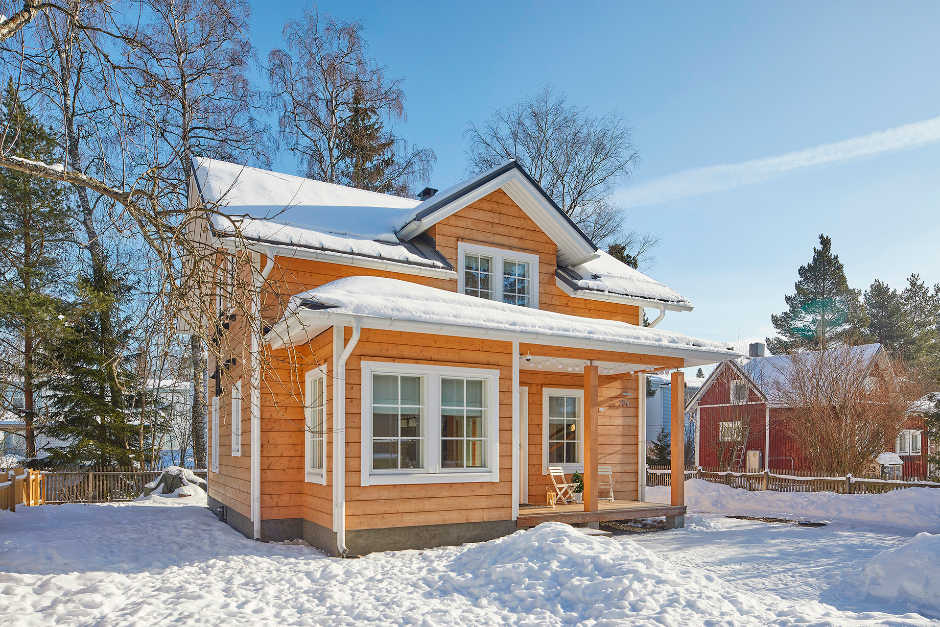 A small, 1.5-storey log house with a pitched roof. The window grilles give the house its distinctive look.