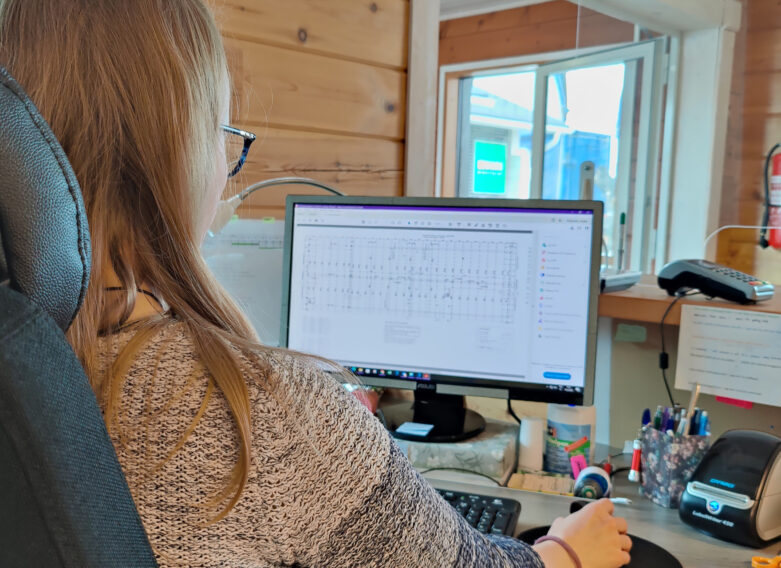 En anställd på Kuusamo Timmerhus sitter vid sitt skrivbord.