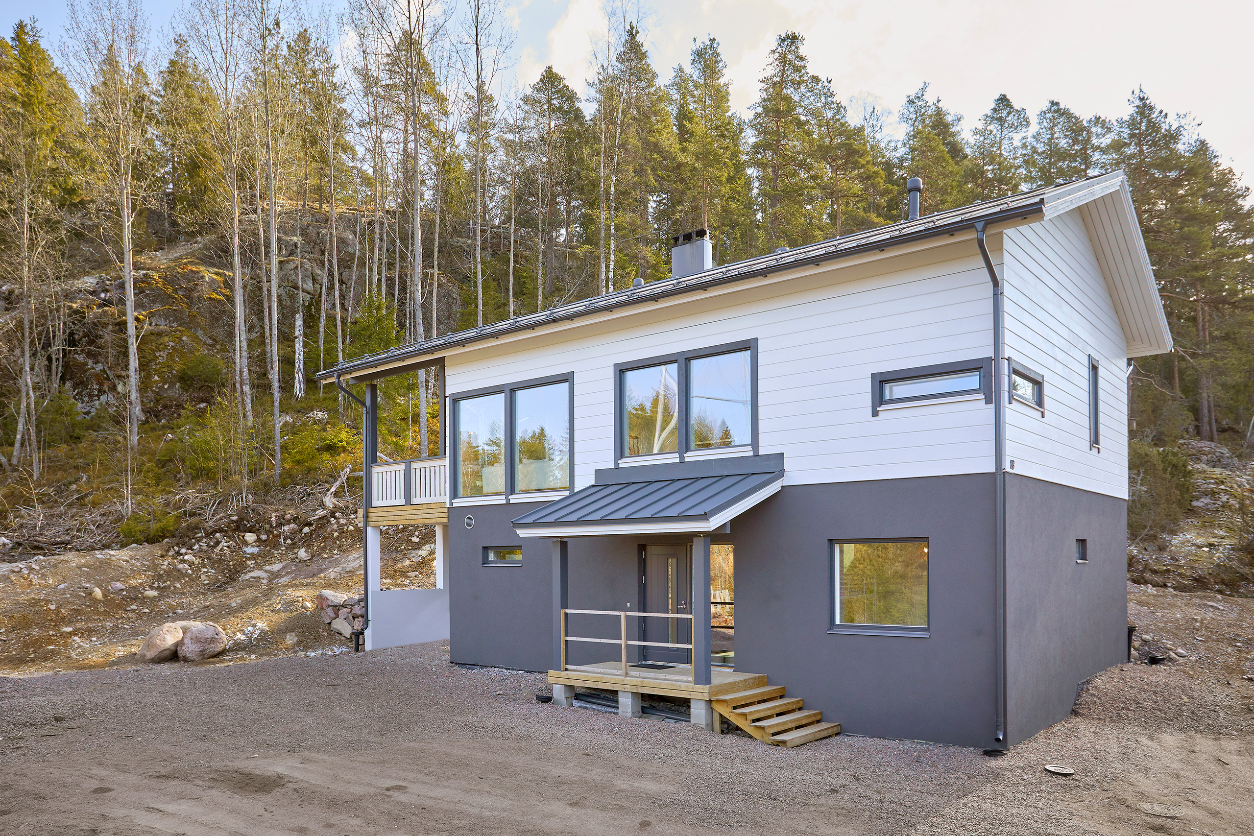 Kaksikerroksinen harjakattoinen hirsitalo.