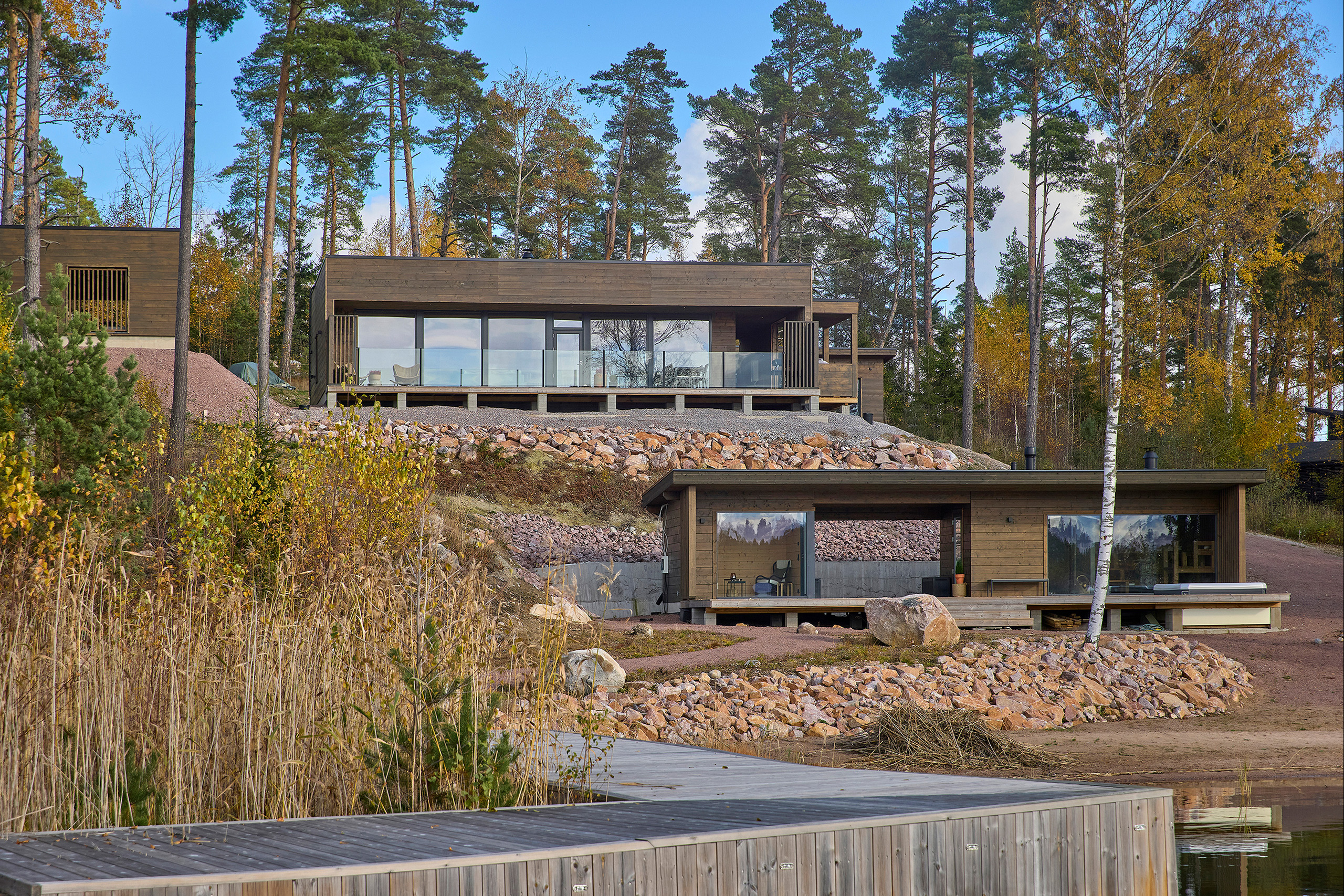 Moderni pulpettikattoinen kakkoskoti Tuuma mereltä päin kuvattuna. Etualalla rantasauna.